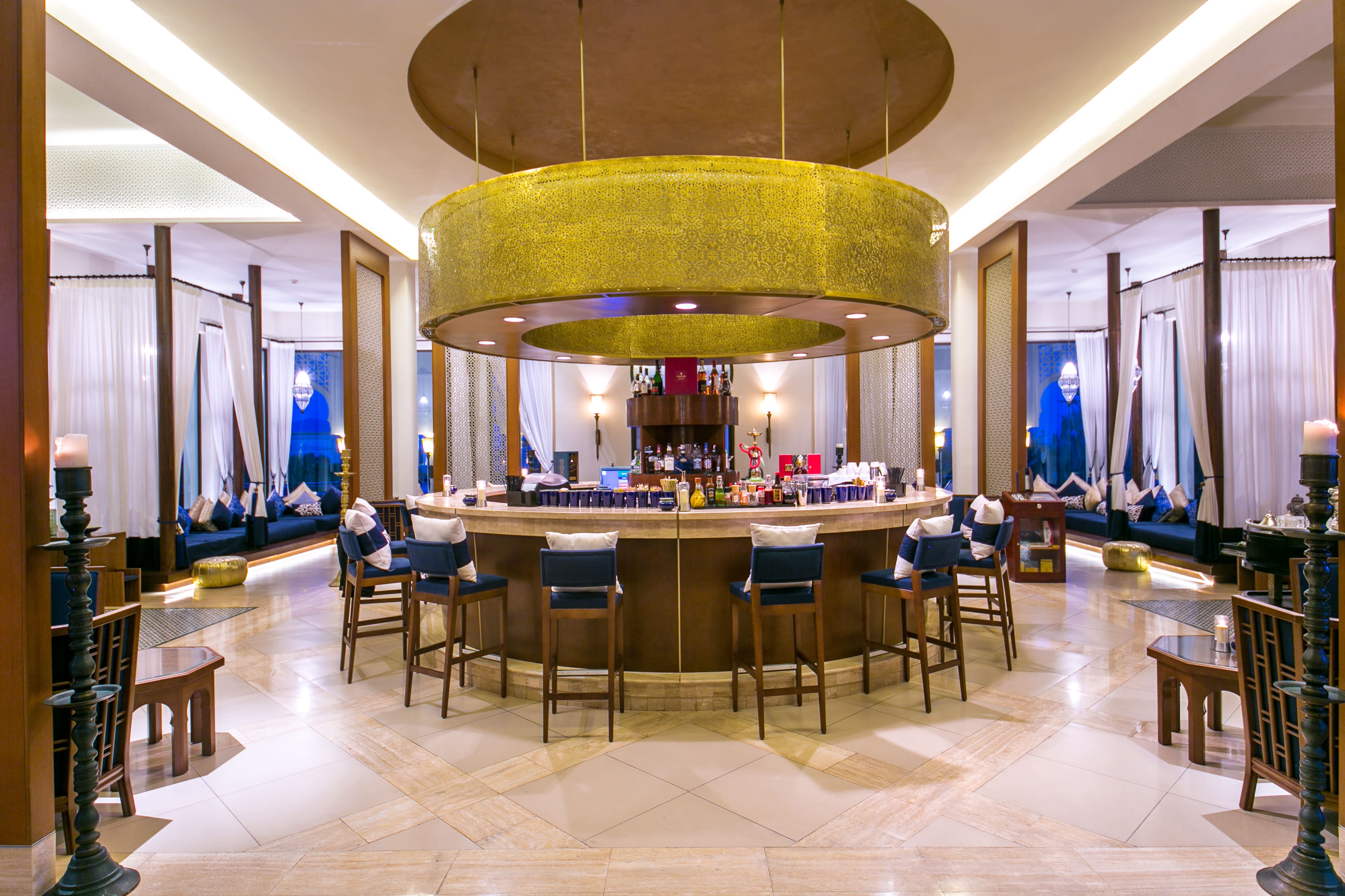 Elegant circular bar with seating beneath golden canopy at Banyan Tree Tamouda Bay Volubilis bar & lounge.